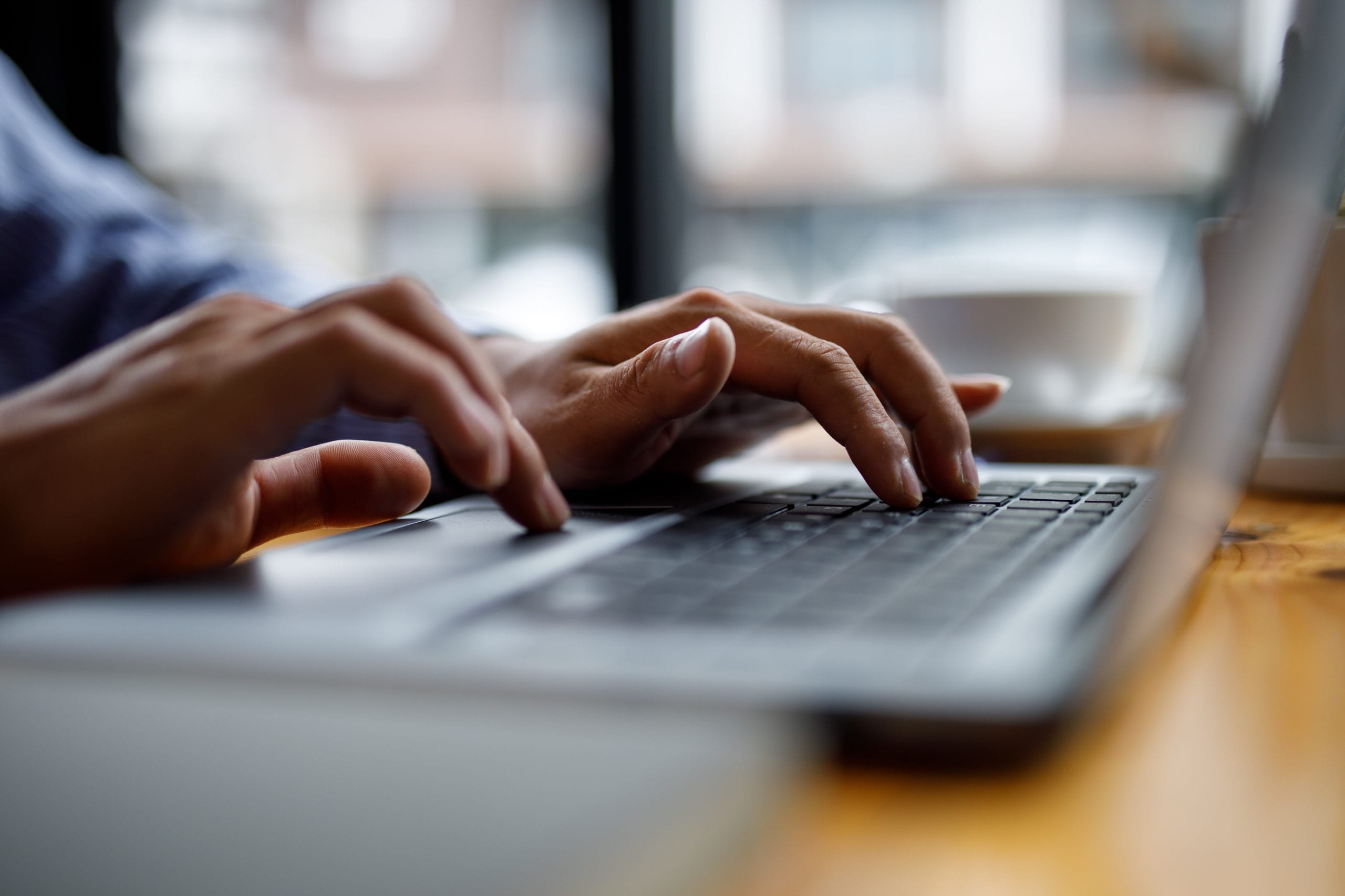 Close-up of hands typing on a laptop, representing KWPMC’s digital estoppel request and HOA questionnaire processing for Florida properties.